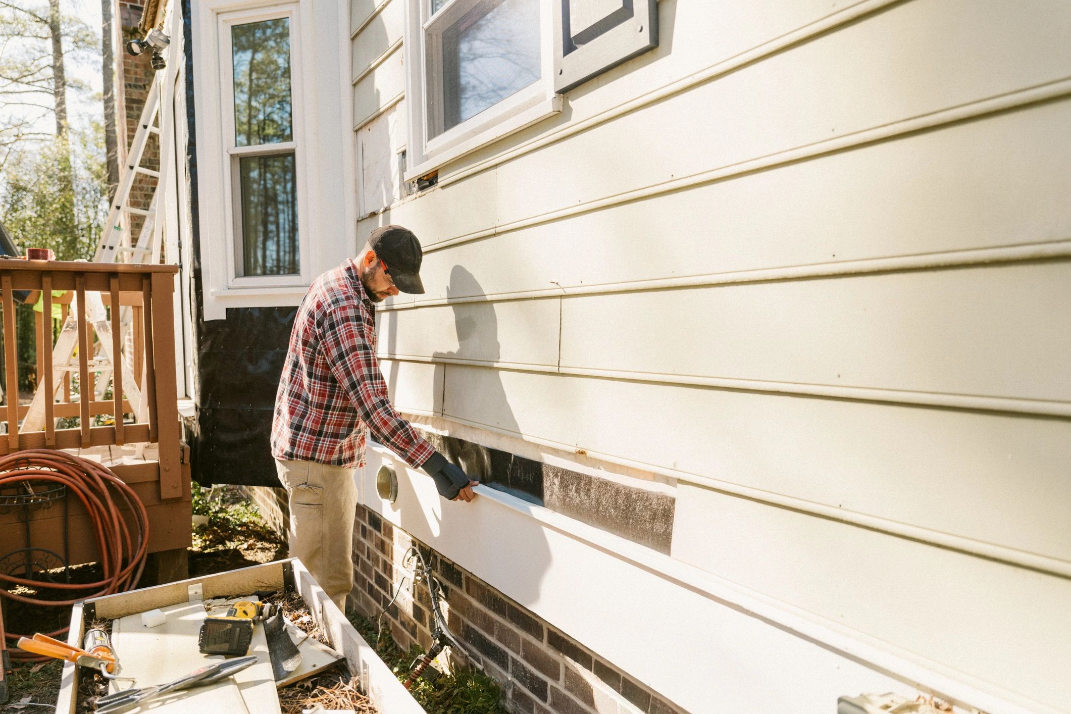 Residential maintenance technician repairing a home exterior